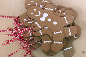 Making-of Weihnachtskarte: Anbringung des Baumwollgarns an den Geschenkanhaenger (Lebkuchenmann) in Handarbeit