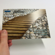 Druckveredelung im UV-Offsetdruck: Haptisch und olfaktorisch interessante Postkarte mit Duftlack (Holz) und Relieflack (Steine)